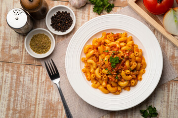 Stir fried macaroni with tomatoes sauce and mince pork on white plate.Top view