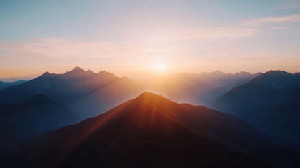 Breathtaking sunrise over majestic mountains, casting warm light and shadows across landscape, creating serene and tranquil atmosphere.