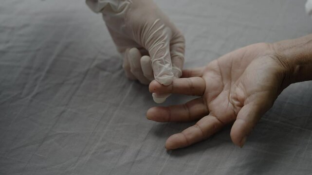 close up doctor pricking senior finger with a small lancet for a blood glucose level screening. diabetes mellitus test