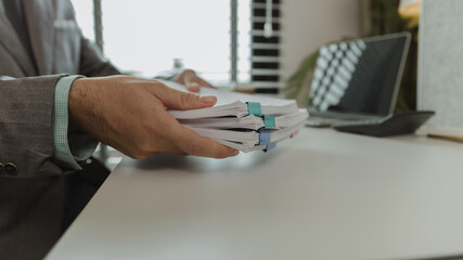 An office worker is putting important documents together to keep everything safe. A businessman is...