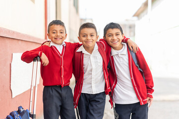 Portrait of three elementary school students with uniform and backpack on the street