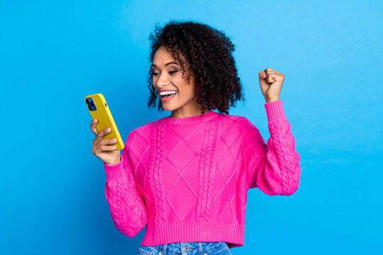 Photo of nice young girl use phone raise fist wear pink sweater isolated on blue color background