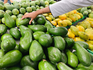 Hand choosing avocado in a supermarket