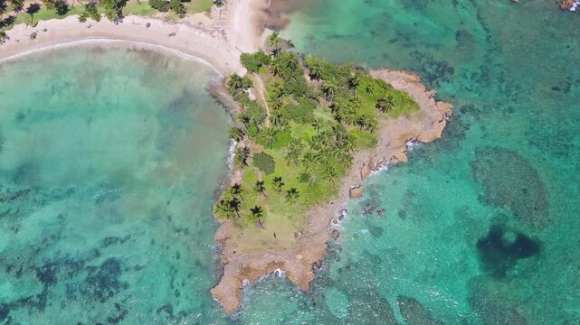 Drone rotating above a bay with palm trees and rocky beaches in the Caribbean