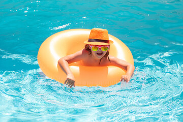 Summer vacation on pool water. Child boy in swimming pool with inflatable ring. Kids swim in water pool on summer vacation. Swim for child on float. Beach sea and water fun.