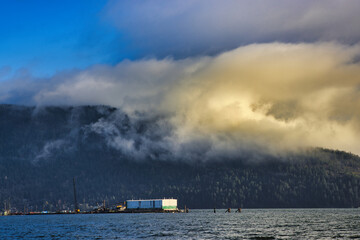 Fog hangs over sailboats and floating houses anchored in Cowichan Bay, off Vancouver Island; Duncan, British Columbia, Canada