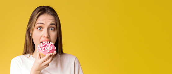 Young Lady Eating Donut, Preferring Unhealthy Food, Posing Over Yellow Background With Guilty Face Expression, Empty Space