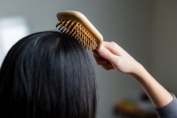 Fototapeta premium Woman Brushing Long Black Hair at Home
