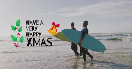 Image of have a very happy xmas over senior biracial couple with surfboards on beach