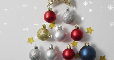 Fototapeta premium Image of snow falling over christmas baubles and stars