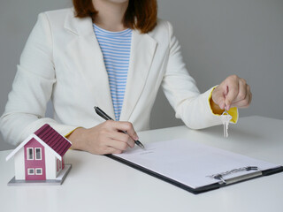 Pretty real estate agent signs documents and hands over house keys to client House selling concept...