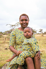 A young African mother playing with her baby outdoors.