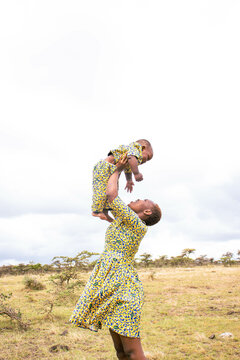 A young African mother playing with her baby outdoors.