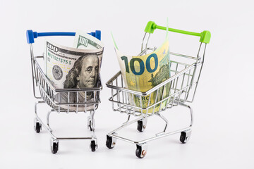 100 US dollar and 100 euro bills in a miniature shopping cart from a supermarket