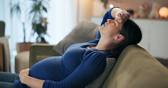 House, tired and pregnant woman on sofa, pain and discomfort in living room. Apartment, pregnancy and person on couch, fatigue or pressure with cramps, contractions or exhausted with breathing