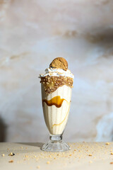 Classic milkshake in wine glass on background. Milkshake with milk, ice cream, kulfi , cherry and whipped cream in minimal style. Vanilla shake with ice cream and coloured decoration in glass
