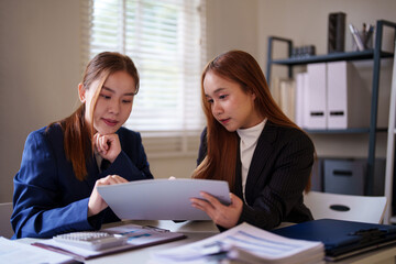 Two businesswomen reviewing a document together, showing teamwork and cooperation in a professional...