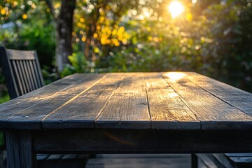 Naklejka premium Wooden table in a garden setting with sunset light.