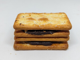 Front view of stacked chocolate sandwich biscuits emphasizing their crunchy texture and creamy filling. The image captures the inviting look of these snacks, perfect for dessert enthusiasts.