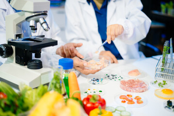 Fototapeta premium Team of scientists examining food samples in a lab with microscopes. Perfect for themes of food science, biotechnology,