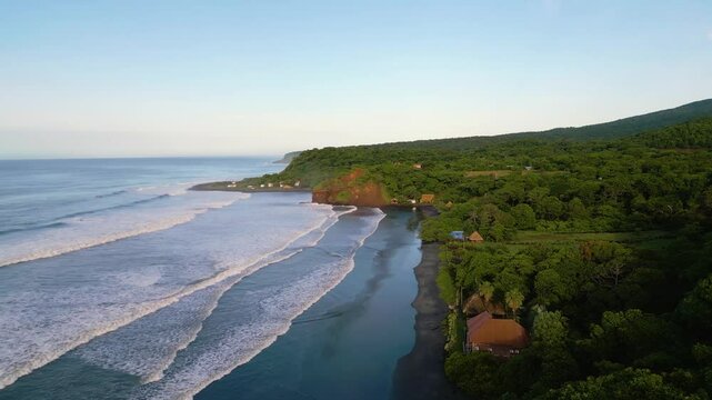 El Salvador beach aerial view of secluded surf spot of El Cuco called Punta Mango with small huts and shacks and tranquil ocean setting - Dolly In