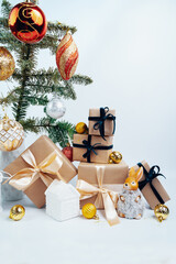 Christmas toys on the Christmas tree. Space for text. Christmas gifts in craft paper with a blue bow. Eco friendly trendy zero waste packaging, holiday mood concept, making gifts.