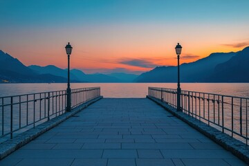 Fototapeta premium A long pier extends into a calm lake at sunset, with mountains in the distance.