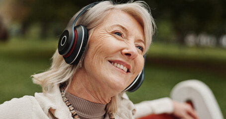 Senior, happy woman or headphones with music at park for audio streaming or radio podcast in nature. Mature, female person or earphones with smile in joy for sound, listening or outdoor entertainment