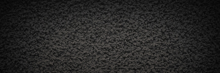 The texture of the gray wall. Decorative plaster. Rough grainy bumpy surface. Dark wide panoramic background for design. Shaded vintage texture with vignette.