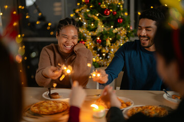 men and women holding sparkler fireworks in a party with Christmas tree. young couple Asian people enjoy celebrating Christmas and New Year. happy and celebrate with food wine and friendship for love,