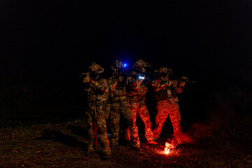 Fototapeta premium A group of military men in combat gear patrol in the middle of a desert and tropical jungle. Soldiers in full combat gear in dry weather conditions assemble and march on a mission.