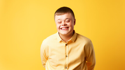Obraz premium Portrait of smiling laughing teenager guy with Down syndrome yellow background.