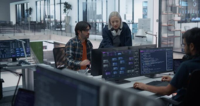 Young Team of Specialists Working on Desktop Computer and Having a Discussion at a Workplace. Young Female and Male Software Developers Talking About an Artificial Intelligence Project