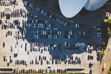 Aerial top down view giant car parking lot in morning full of cars by office town hall Tbilisi building. Car registration Georgia country. Cars moving in busy parking lot stand in shadow in hot day