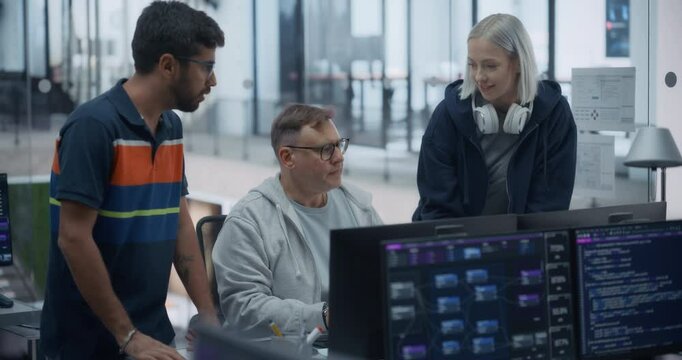 Two Young Diverse Colleagues Standing Next to a Senior Developer, Working on a Computer and Talking at a Workplace. Female and Male Software Developers Discussing a Solution for Their AI Project