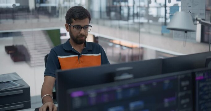 Handsome Young Indian Male Specialist Working on Computer Together with Professional Colleagues. South Asian Manager Wearing Glasses, Working on Software Engineering in a Corporate Office Facility