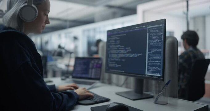 Portrait of a Young Female Software Developer Working on Computer in Office, Writing Software Code. IT Programming Department Researching and Developing Commercial Internet Products. Zoom Out Footage