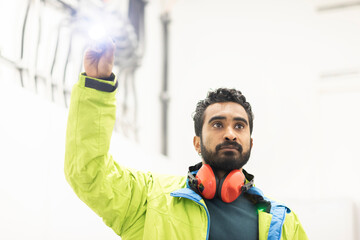 young engineer with beard checking with a flashlight