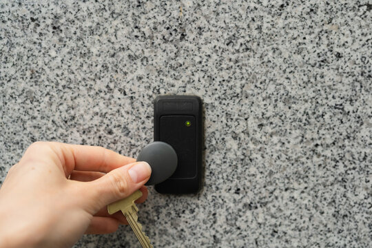 Woman's hand holding key fob next to the door opening device