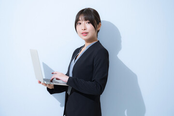 Fresh young serious woman in business image with light blue background, wearing a suit and opening...