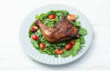 Grilled chicken legs with tomatoes and salad . Top view