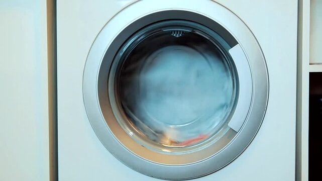 Modern washing machine during spin cycle in domestic laundry room