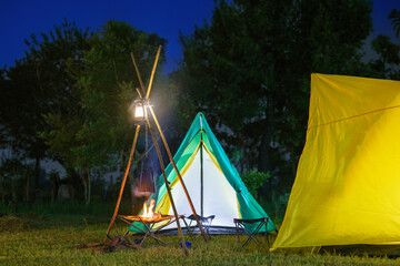 camping tent in the forest with green trees, camping in the forest at night, Small gas lantern on green grass