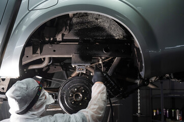 The master sprays an anti-corrosion compound on the bottom of the car.