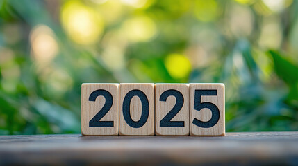 A wooden block with the number "2025" on a green bokeh background