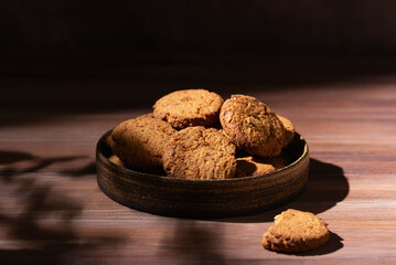 Homemade oatmeal cookies in a plate on a brown wooden table.