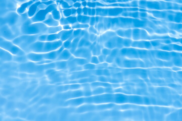 Blue water with ripples on the surface. Defocus blurred transparent blue colored clear calm water surface texture with splashes and bubbles. Water waves with shining pattern texture background.