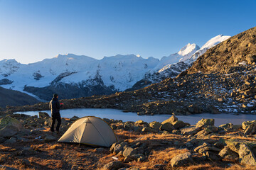 A hiker enjoying his coffee at a beautiful campsite in the Bernina mountain range. Switserland.