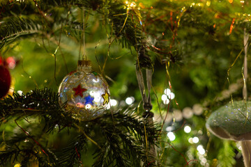 Frosted glass Christmas bauble decoration with red, blue, yellow and green stars design. Christmas tree ornament. Shallow depth of field. Bokeh. Festive scene.