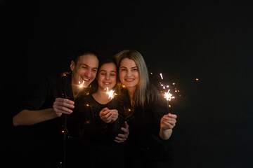 Young family with sparklers at Christmas time on a black background